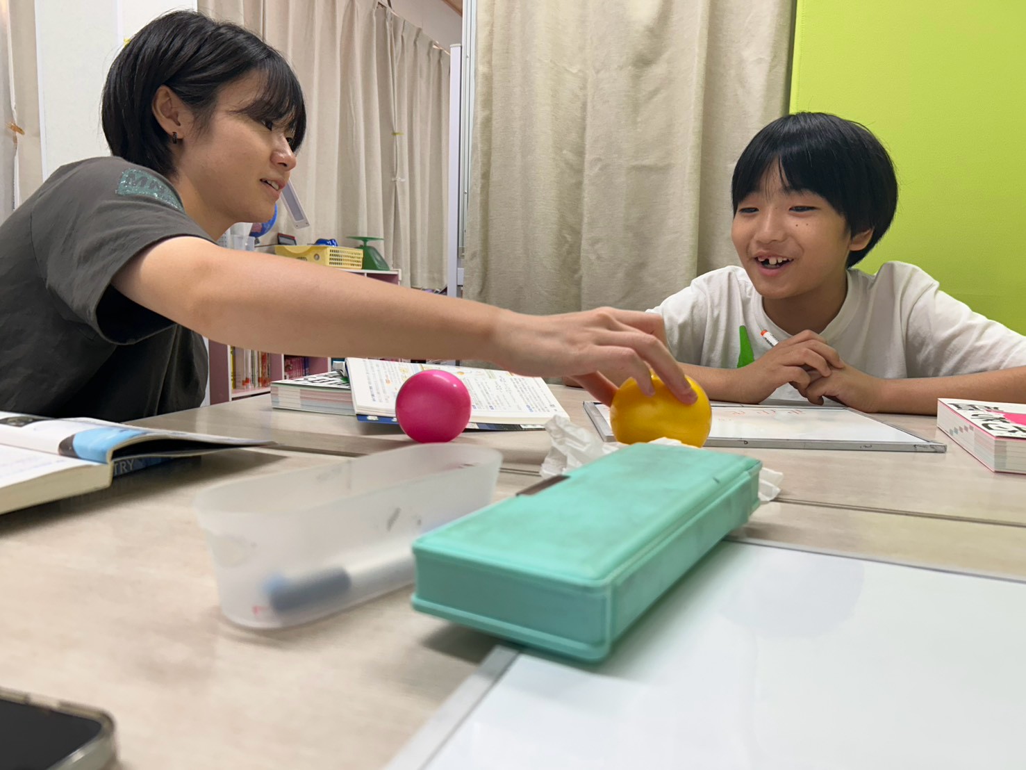 大学生講師とお子さまがボールを使って学ぶ様子